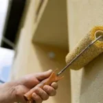 Exterior painting, using a roller to paint stucco